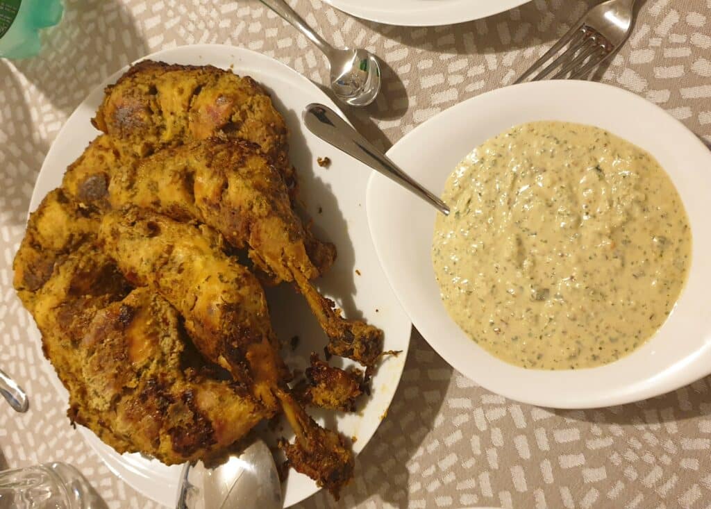 Plat de cuisses de poulet entières cuites avec un bol de sauce à la crème de sésame